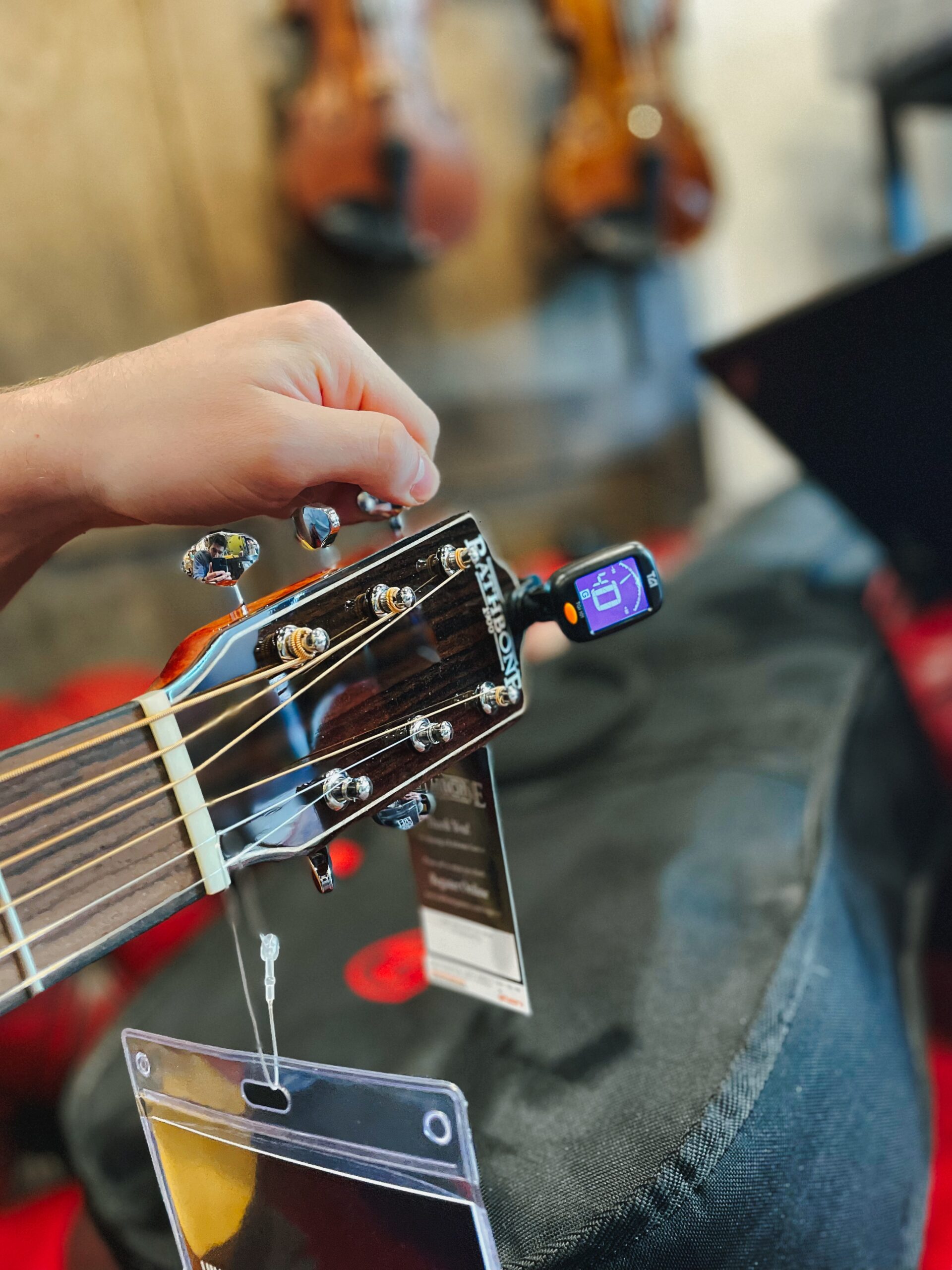 Guitar Accessories - tuning with clip-on tuner in a music shop. Finding D chord